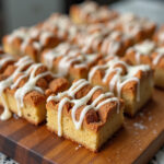 Freshly baked Cinnamon Roll Bliss Bars with icing drizzle, perfect for dessert.
