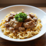 Classic Beef Stroganoff with egg noodles and parsley garnish, ready to eat.