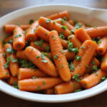Delicious creamy honey roasted carrots garnished with herbs, ready to serve.