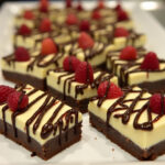 Finished Decadent Chocolate Chip Cheesecake Bar Bites with chocolate drizzle and berries.