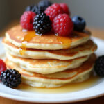 Finished low-carb high-protein cottage cheese pancakes with berries and syrup.