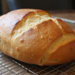 Perfectly baked bread loaf cooling on a rack, made with a bread machine.