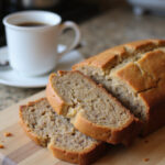 Freshly baked high altitude banana bread slice on a cutting board.