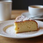 Delicious slice of gluten-free cake with powdered sugar and coffee.