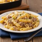 Serving creamy cheesy penne with garlic butter ground beef, featuring a delicious and vibrant presentation on a rustic table.