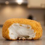 Close-up of a crispy deep fried marshmallow, highlighting its fluffy center and crunchy exterior, perfect for desserts.