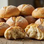 Freshly baked crusty chewy French bread rolls on a wooden surface, emphasizing the golden crust and soft, airy texture ideal for any meal.