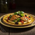 Plated Mediterranean Chicken Pasta Salad ready to serve, garnished with basil and olives, ideal for a summer meal or gathering.