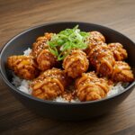 Final presentation of the BEST Bang Bang Chicken Bowl featuring crispy chicken, creamy sauce, and rice, artfully garnished for a delicious meal.